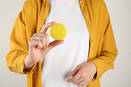 Woman with blank yellow button badge on light background, closeupの写真素材