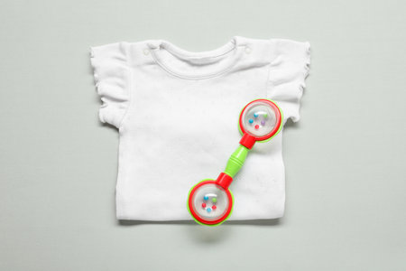 Baby rattle and body on light background, top view