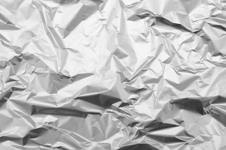 Crumpled silver foil as background, top viewの写真素材