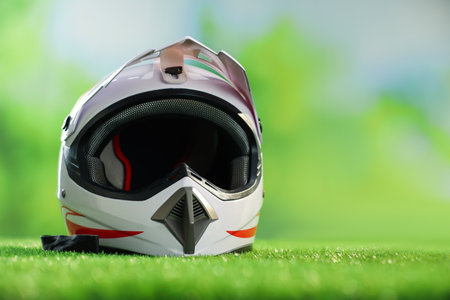 Modern motorcycle helmet with visor on green grass, space for textの写真素材