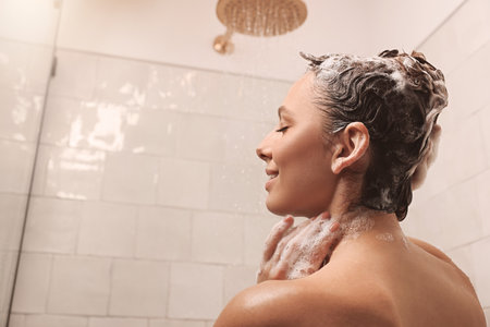 Young woman washing hair while taking shower at home. Space for textの写真素材