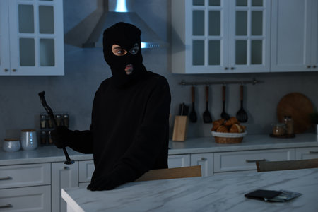 Thief wearing balaclava with crowbar in foreign house. Burglaryの写真素材