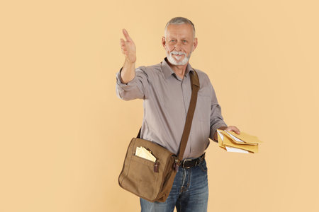 Happy postman with brown bag delivering letters on beige background