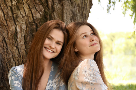 Two beautiful twin sisters near tree outdoorsの写真素材