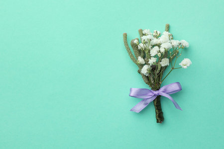 Small stylish boutonniere on turquoise background, flat lay. Space for textの写真素材