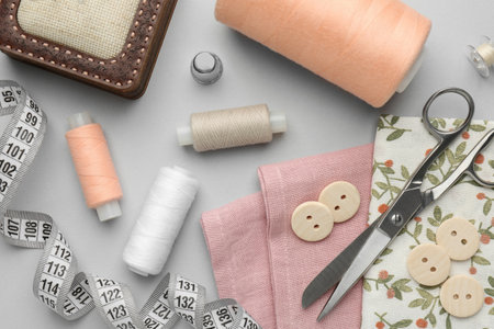 Flat lay composition with different sewing supplies on light gray background