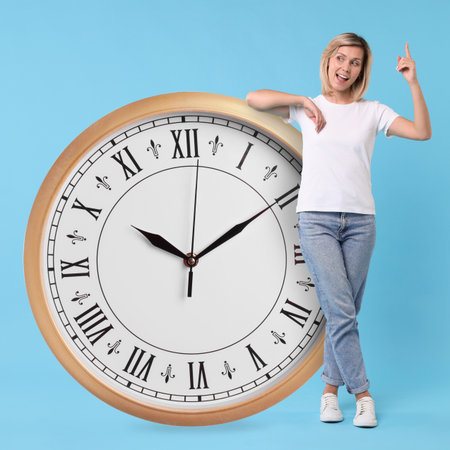 Woman and big clock on light blue background