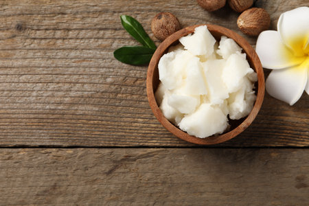 Natural shea butter, nuts and plumeria flower on wooden table, flat lay. Space for textの写真素材