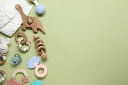 Different baby rattles and diapers on color background, flat lay. Space for text