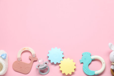 Colorful rattles and pacifier on pale pink background, flat lay with space for text. Baby accessoriesの写真素材