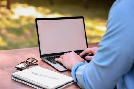 Freelancer working with laptop at table outdoors, closeup. Remote jobの写真素材