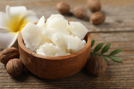 Natural shea butter, nuts and plumeria flower on wooden table, closeupの写真素材