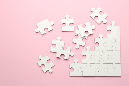 White puzzle pieces on pink background, top viewの写真素材