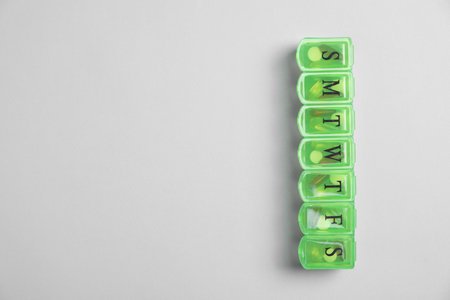 Different pills in organizer on light background, top view. Space for textの写真素材