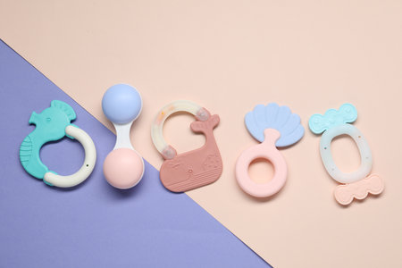 Bright rattles on color background, flat lay. Baby accessories