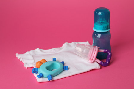 Baby rattle, body, bottle and nibbler on crimson backgroundの写真素材