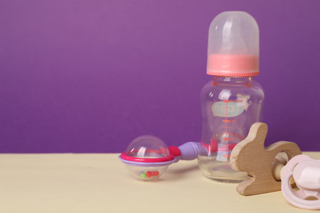 Baby rattles, pacifier and bottle on beige table. Space for textの写真素材