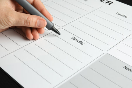 Timetable. Man making schedule using weekly planner at table, closeup