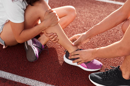 Sports injury. Man helping woman with leg pain at stadium, closeup