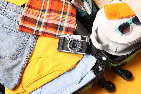 Open suitcase with traveler's belongings on yellow background, top viewの写真素材
