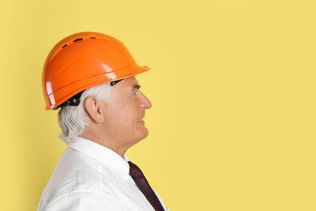 Engineer in hard hat on yellow background, space for textの写真素材