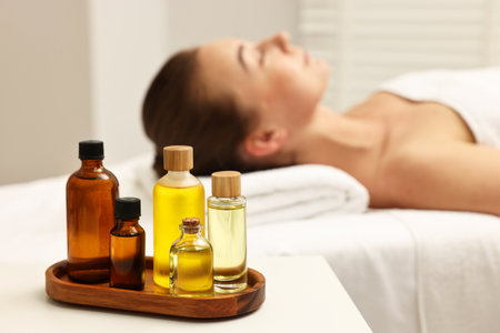 Aromatherapy. Woman relaxing on massage couch in spa salon, focus on bottles of essential oilsの写真素材
