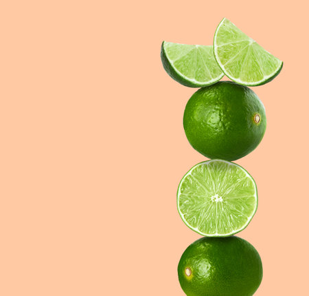 Stacked fresh limes on pink background, space for text