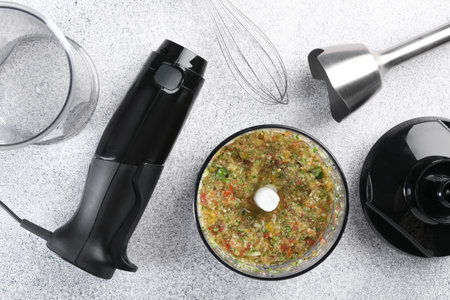 Hand blender kit and mixture of ingredients on light gray table, flat lay