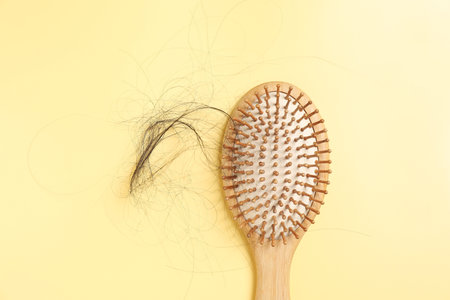 Wooden brush with lost hair on yellow background, top viewの写真素材