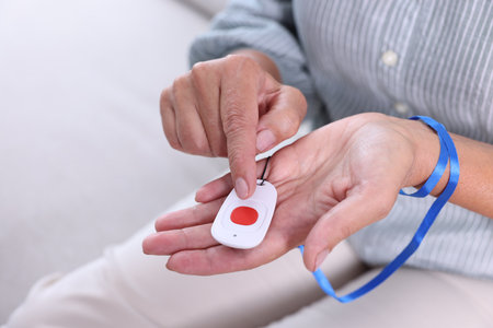 Senior woman pressing emergency call button at home, closeup