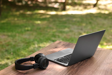 Laptop and headphones on wooden table outdoors. Remote workの写真素材