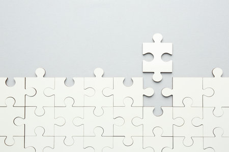 White puzzle pieces on gray background, top view. Space for textの写真素材