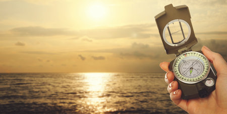 Woman holding compass on beach near sea, closeup. Banner design with space for textの写真素材