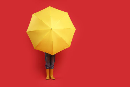 Little boy with yellow umbrella on red background, space for textの写真素材