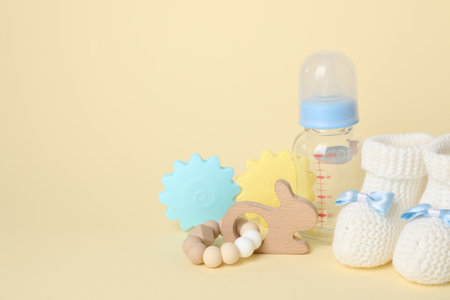 Baby toys, booties and bottle on beige background. Space for textの写真素材