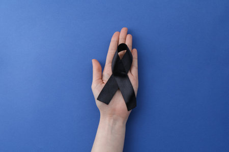Woman with black awareness ribbon on blue background, top viewの写真素材