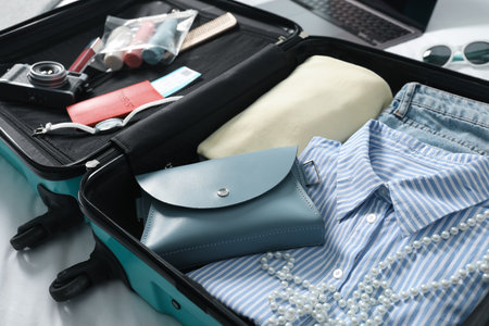 Open suitcase with traveler's belongings on bed, closeupの写真素材