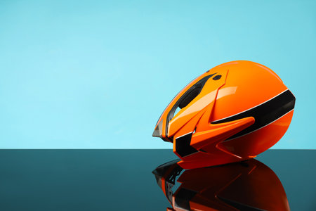 Modern motorcycle helmet with visor on mirror surface against light blue background. Space for textの写真素材