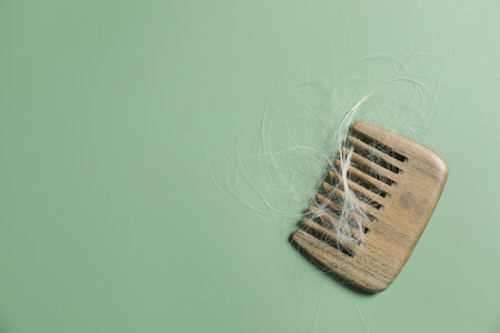 Comb with lost hair on green background, top view. Space for textの写真素材