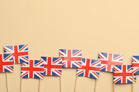 Small paper flags of United Kingdom on beige background, top view. Space for textの写真素材