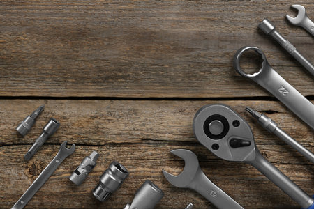 Different auto mechanic's tools on wooden table, flat lay. Space for text