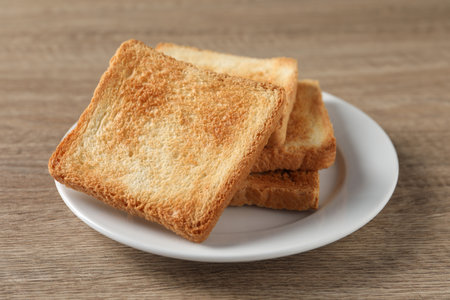Slices of delicious toasted bread on wooden table, closeupの写真素材