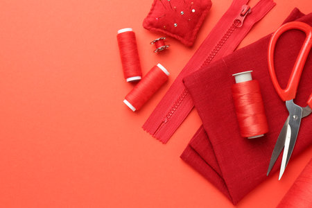 Flat lay composition with different sewing supplies on coral background. Space for textの写真素材