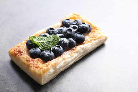 Tasty puff pastry with blueberries and mint on gray table, closeup. Space for textの写真素材