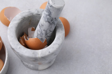 Broken eggshells, mortar and pestle on gray table, closeup. Space for textの写真素材