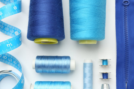 Flat lay composition with different sewing supplies on white background