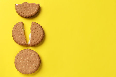 Tasty sandwich cookies on yellow background, top view. Space for textの写真素材