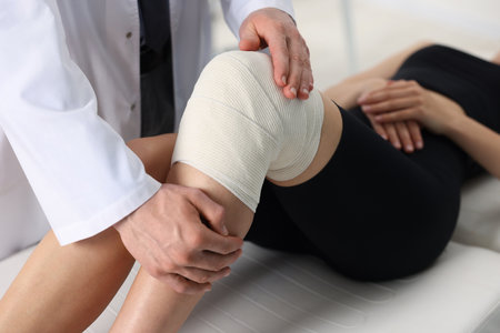 Sports injury. Doctor examining patient's knee in hospital, closeupの写真素材