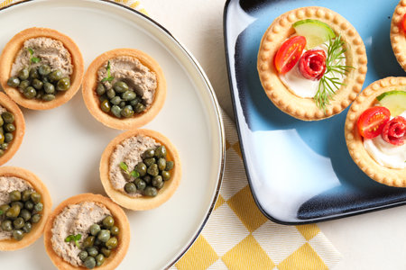 Delicious canapes with pate, dry smoked sausages and capers on light table, flat layの写真素材