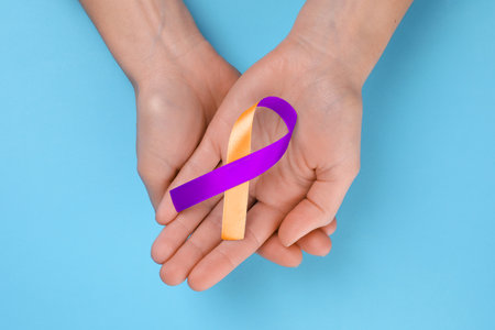 World Psoriasis Day. Woman with orange and orchid ribbon as symbol of support on light blue background, top viewの写真素材
